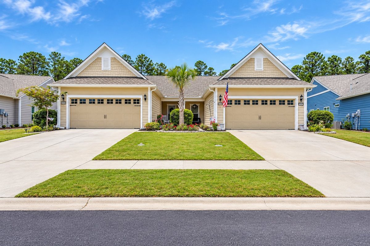 Paired villas with a palm tree between the driveways at Del Webb Grande Dunes